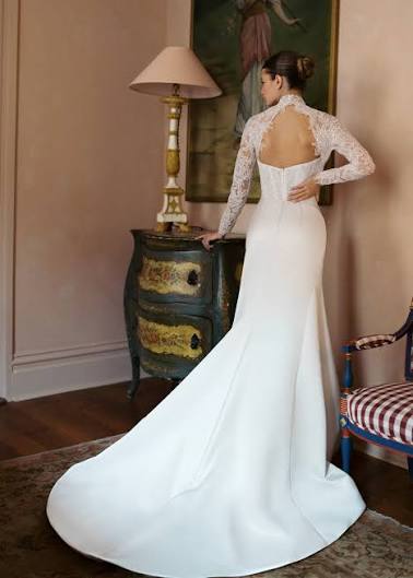 Elegant bridal gown featuring a fitted silhouette and lace detailing, showcased against a vintage-inspired room setting.